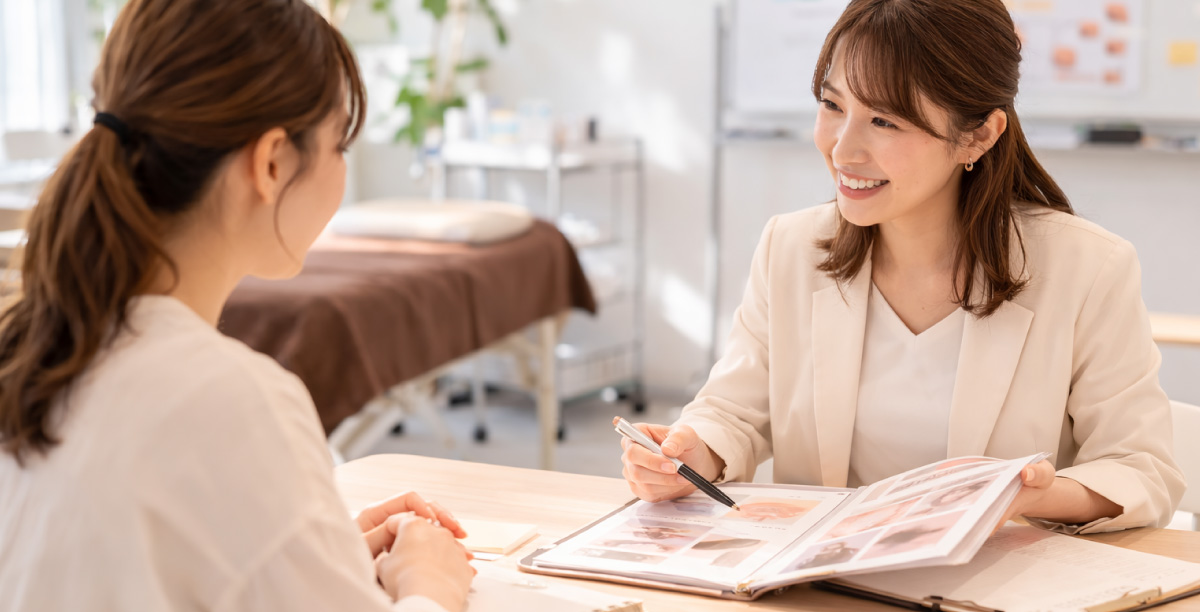 医療アートメイクスクールで講師が資料を見せながら、学習の進め方や不安を相談している卒業生の様子