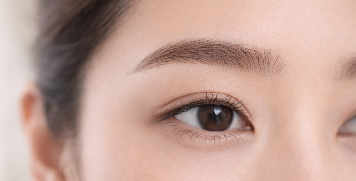 自眉の毛流れに沿って毛並みの医療アートメイクが自然になじんでいる、片眉と目元の近接イメージ。